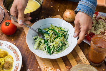 Green cucumber and cabbage salad with walnuts, olive oil and sunflower seeds sauce dressing. Raw vegan vegetarian food. Woman hands holds salad. Lunch or dinner time