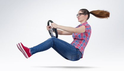 Young girl in glasses driver car with a wheel