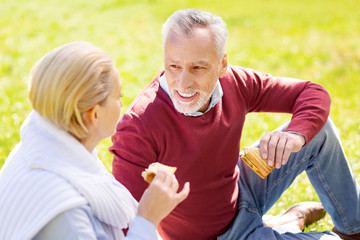 Pleasant interaction. Joyful positive man talking to his wife while having a picnic with her