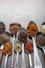 Different spices in  spoons on a wooden background.
