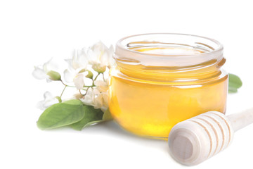Honey in a glass jar with a sprig of acacia and a wooden spoon for honey. isolated