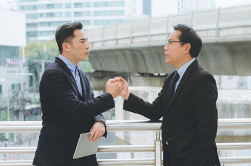 Fototapeta premium business man shaking hand at outdoor in modern city for complete business deal together successful. teamwork concept. partnership concept and dealership concept.