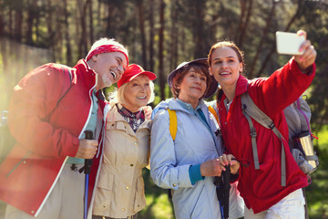 Say cheese. Inspired aged people taking pictures while hiking with their guide