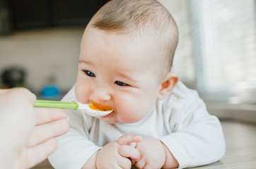 baby with blue eyes eats pumpkin puree