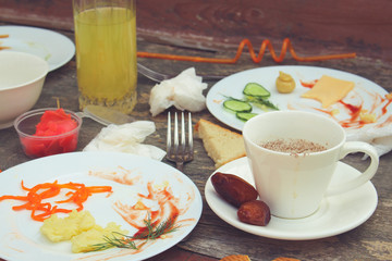 Messy table after party. Leftover food, spilled drinks, dirty dishes. Toned image. 
