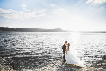 Elegant stylish happy wedding couple, bride, gorgeous groom on the background of sea and sky