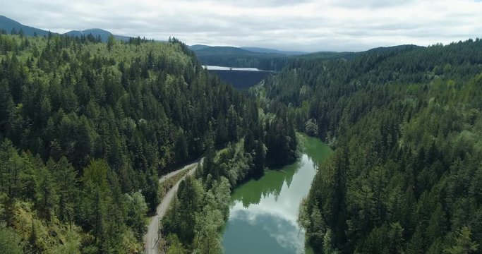 Aerial Flying Towards Dam Above River Holding Back Lake