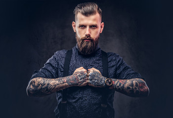 Severe old-fashioned hipster guy in a blue shirt and suspenders, posing in a studio.
