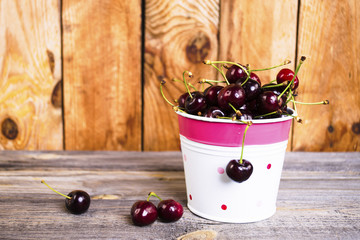 Cherry in a decorative bucket on an old wooden background