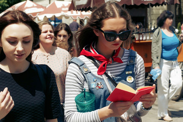 stylish woman hipster  reading book and walking with friends in europe city street, travel and learning concept