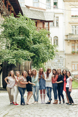 Fototapeta premium Group of happy stylish women posing on background of old european city street, travel or celebrating friendship concept, moments of happiness