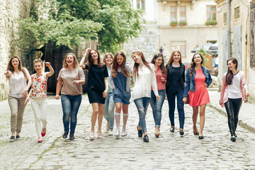 Fototapeta premium Group of many happy women walking having fun on background of old european city street, celebrating friendship concept, moments of happiness