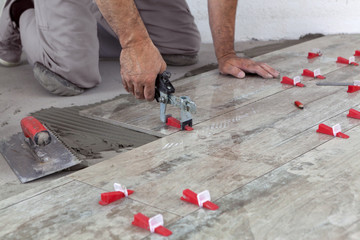 Ceramic Tiles. Tiler placing tille in position with lash tile leveling system