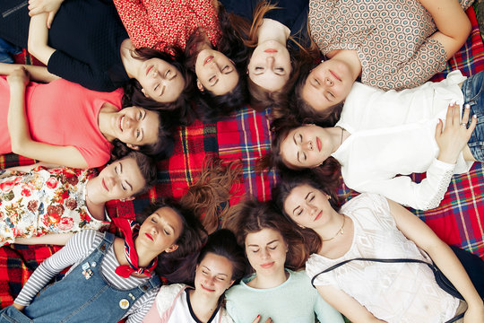 happy group of women faces in circle posing and smiling on picnic top view, lying on blanket, calm and joyful moments celebration in summer park