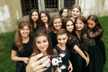 gorgeous women group in black dresses taking selfie having fun and laughing in the city. stylish lady party with gothic theme. elegant girls