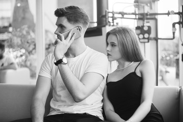 Romantic couple enjoying the company of each other in black and white. Sexy girl in black dress with boyfriend in restoration waits while the guy speaks by phone. Fashion couple. love.