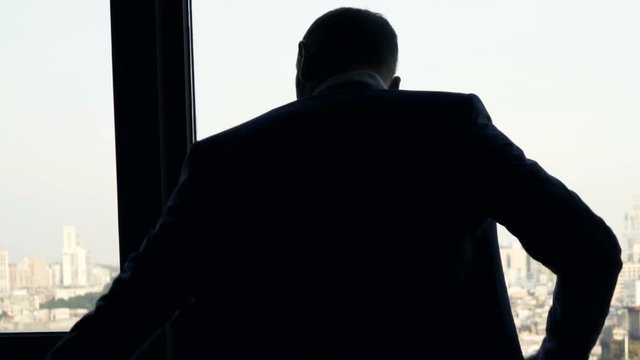 Young businessman putting on jacket standing by window at home
