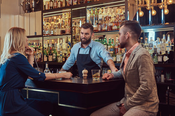 Stylish brutal barman serves an attractive couple who spend an evening on a date.