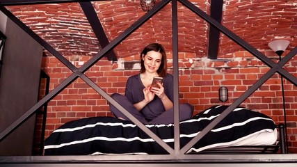 Pretty woman in pajamas sitting with smartphone in mezzanine bedroom
- Powered by Adobe