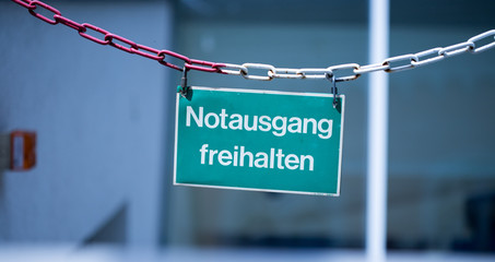 Grünes Notausgang-Schild an Kette, Gebäude, Breitbild