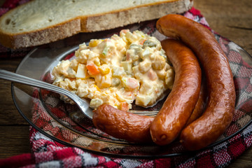 Thin sausages with vegetable salad on plate.