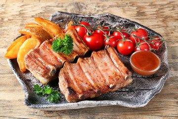 Plate with delicious grilled ribs and garnish on wooden table