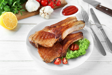 Plate with delicious grilled ribs on table