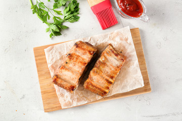 Wooden board with delicious grilled ribs on table