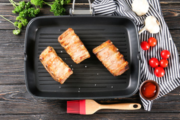 Grill pan with delicious ribs on wooden table