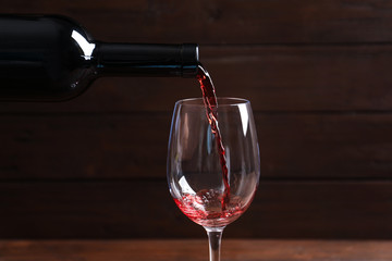 Pouring delicious red wine into glass on blurred background