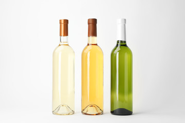 Bottles of expensive white wines on light background