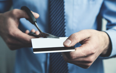 Businessman cutting credit card with scissors.