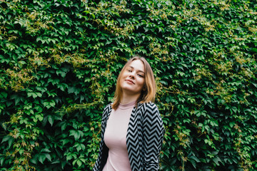 Portrait of a stylish woman against a green foliage background.