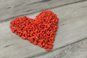 Heap of goji berry (wolfberry - Lycium chinense) dried fruits arranged in shape of heart on a gray...