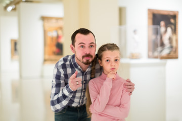 father and daughter regarding paintings in museum
