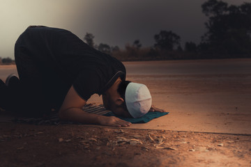 Obraz premium Silhouette Young asian muslim man praying on sunset,Ramadan festival concept