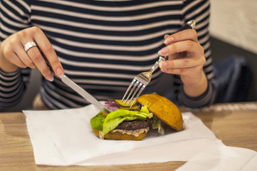 Burger in beautiful female hands. Close-up. Background of no sharpness
