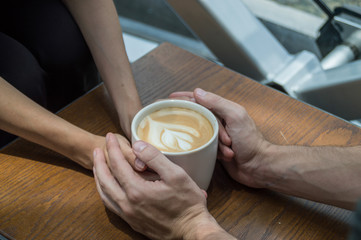 hands holding cups of coffee on rustic wooden table background