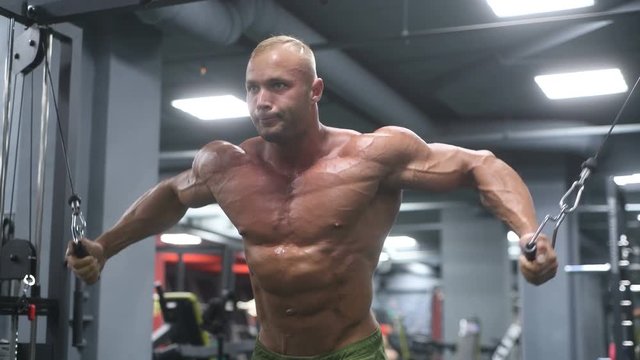 Handsome young fit muscular caucasian man of model appearance workout training in the gym gaining weight pumping up muscle, poses, drinks water  fitness and bodybuilding sport nutrition concept
