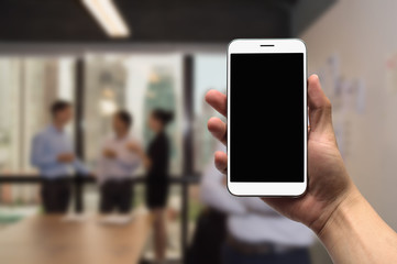Hold  mobile on the background of a group of business people working in an office.