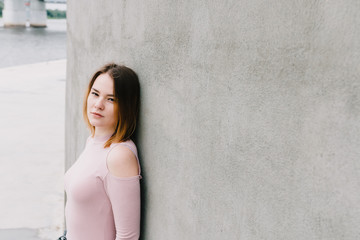 Portrait of a stylish woman on a concrete wall background.