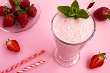Strawberry milkshake in the glass on the pink  background.Top view.