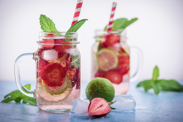 Close up view on lime and strawberry detox drink in glass mason jars on a blue background Selective focus. 12