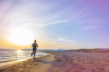 Healthy young fitness woman runner running on sunrise seaside trail