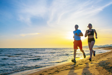 Man and women running on tropical beach at sunset