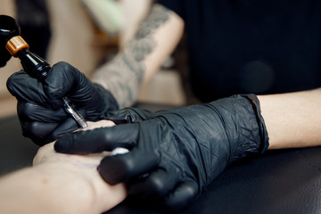 Fototapeta premium Tattoo process machine close-up. master prepares for procedure of drawing