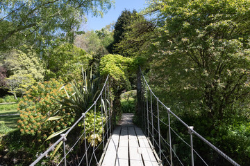 Hanging walk suspension bridge with wooden path leading to park