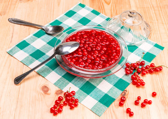 Homemade jam of red currant in a glass bowl, on a wooden table, top view.
