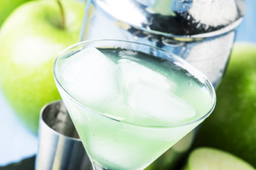 Alcoholic cocktail with green apple and dry vermouth, syrup, lemon juice and ice cubes. Bar tools,...
