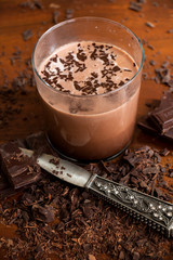ein Glas  Kakao mit Schokoladenraspeln und dekorativen Messer